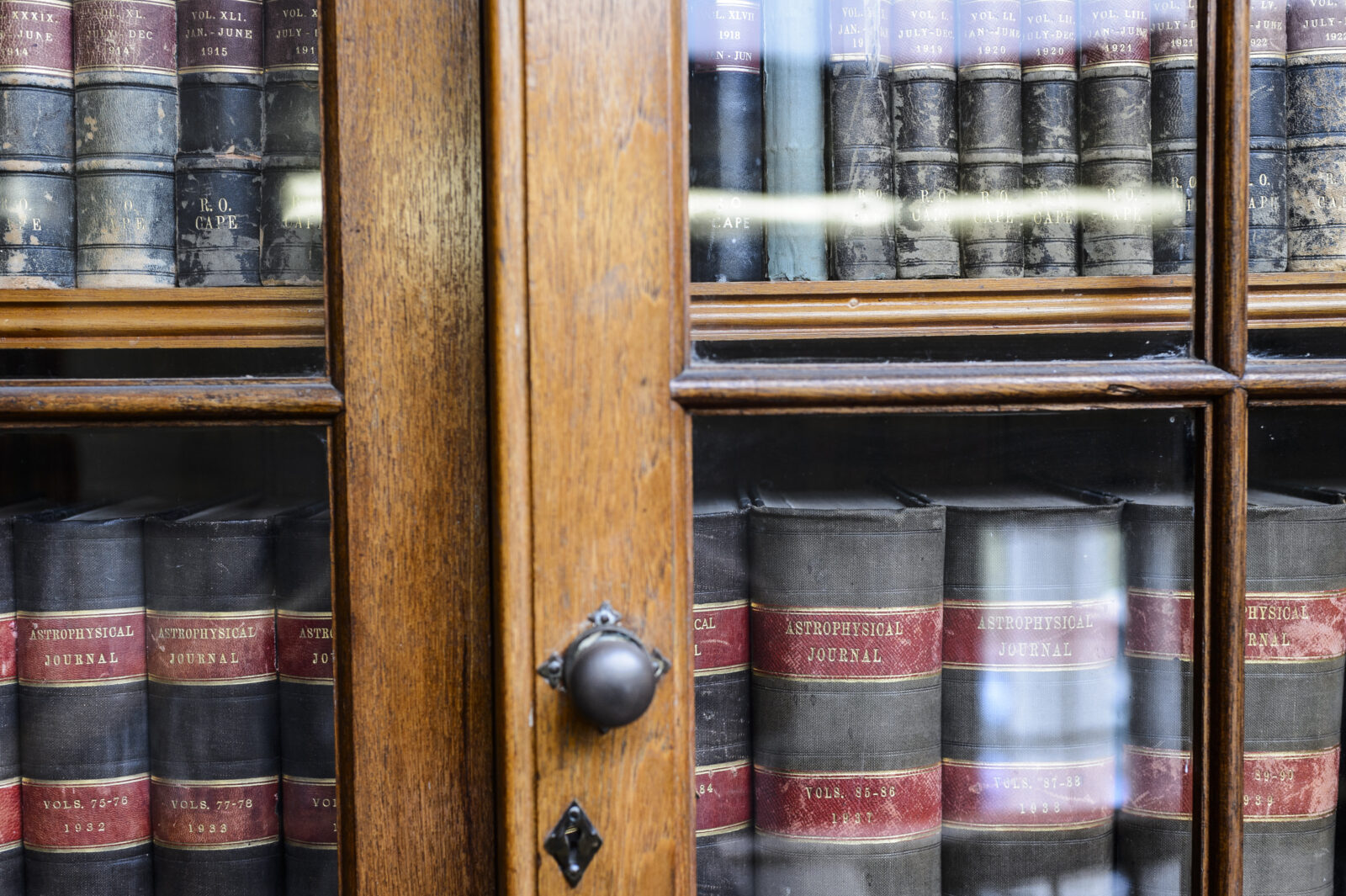 A glass bookcase with a collection of early 1900s-era scientific journals.