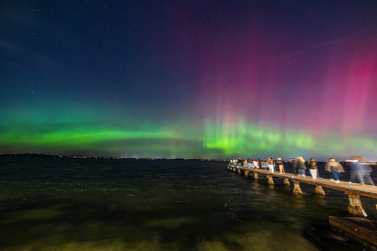A group of students admire the Northern Lights over lake Mendota from the Goodspeed Family Pier.
