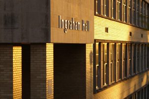 Exterior view of Ingraham Hall's Observatory Dr. entrance, with the setting sun shining on the building.