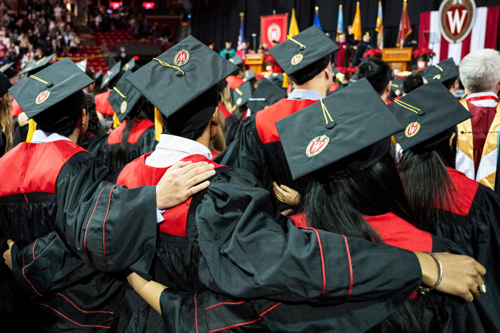 UW students at a graduation ceremony, arms on each other's shoulders, for a rendition of the song "Varsity."