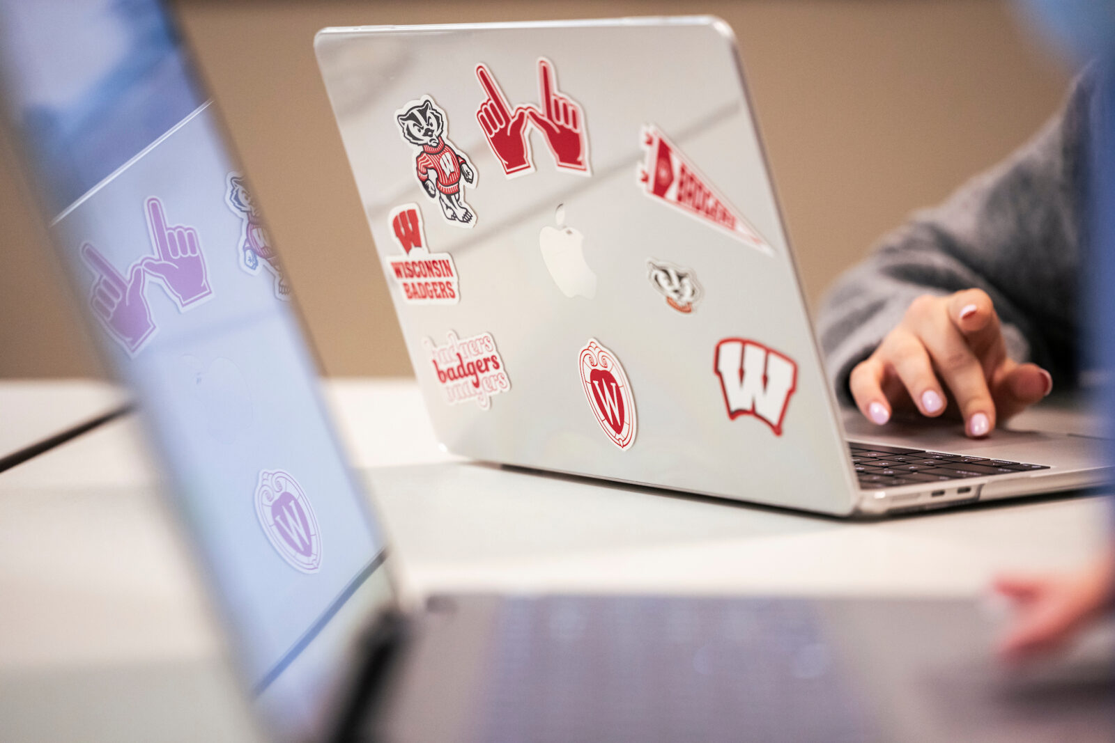 The back of a student's laptop, covered in UW-Madison-themed stickers.