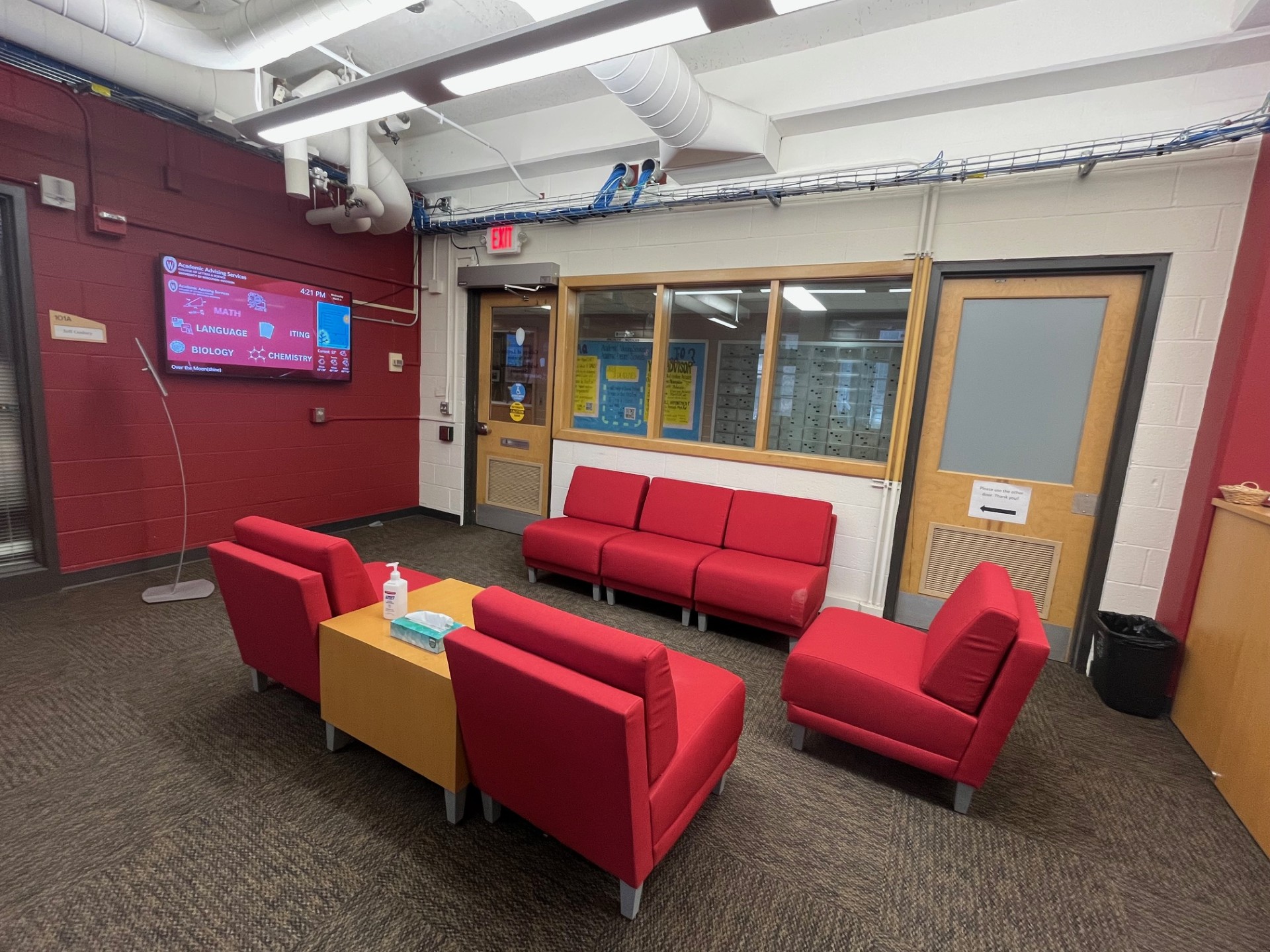 The lobby and waiting area of L&S Academic Services, with a couch, three chairs, and a TV monitor.