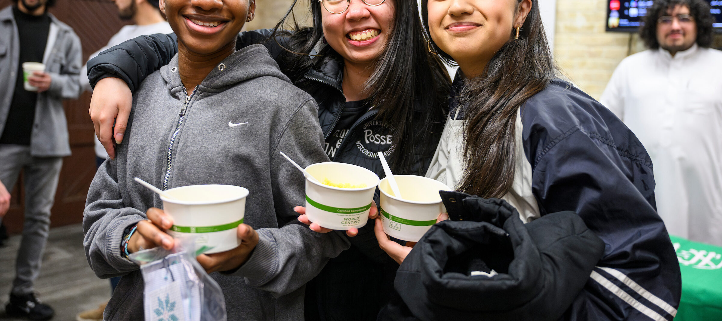 Posse students Daniela Luseko and Vivian Wanjing, and Valerey Aguirre pose for a photo while enjoying Somali food during “A Night at The Bazaar” kickoff event for MENA (Middle Eastern and North African) Heritage Month at the Red Gym at the University of Wisconsin–Madison on March 1, 2024. The event featured cultural clothing, live music, food from across the region, and activities including henna, tatreez embroidery, calligraphy, and glass mosaics. (Photo by Althea Dotzour / UW–Madison)