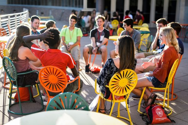 A dozen new students sit in a circle in colorful chairs on the Union Terrace.