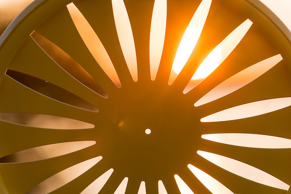 The cutout sunburst design of a silhouetted Memorial Union Terrace chair at the University of Wisconsin-Madison frames the view as the sunset sets over Lake Mendota during a summer evening